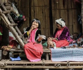 Hill tribe women in colorful traditional attire sorting through fresh bamboo shoots at a local mountain market.