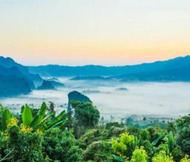 A breathtaking sunrise view over misty limestone mountain ranges and lush valleys in Northern Thailand.
