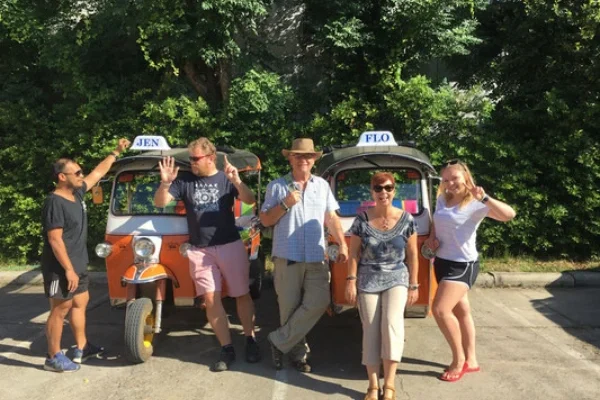 Travelers posing cheerfully with a tuk-tuk during a multi-day trip